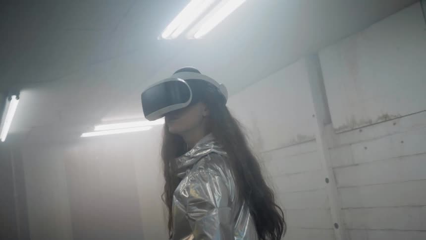 A woman wearing vr glasses looks around while lights flash