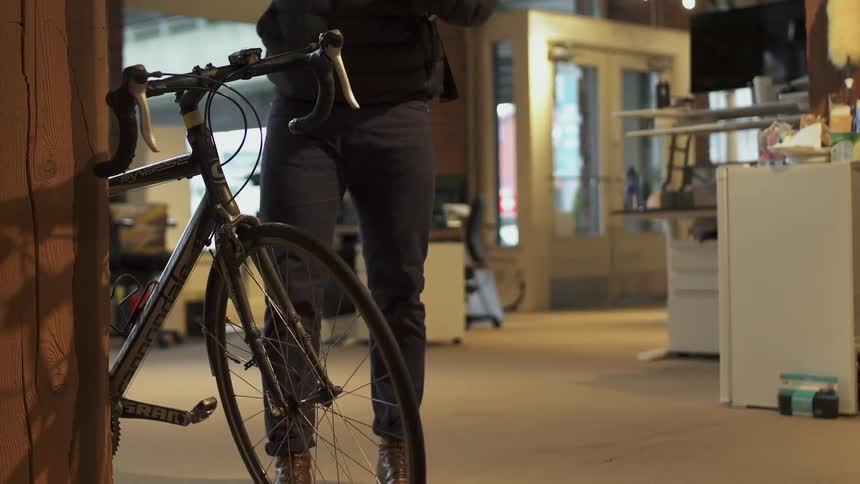 The man parks his bicycle and removes his helmet