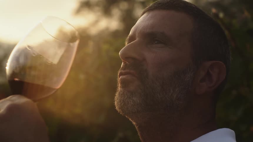A man drinks wine at sunset
