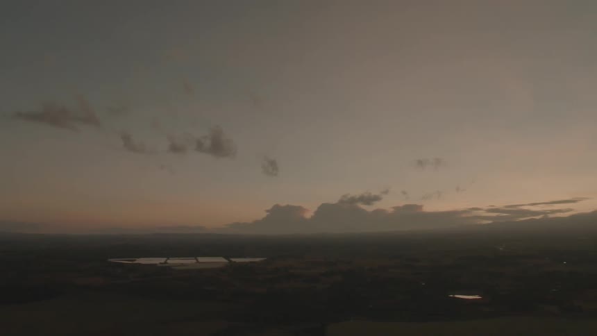 Clouds float above a rural landscape at sunset