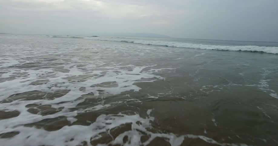 Ocean waves wash ashore a sandy beach