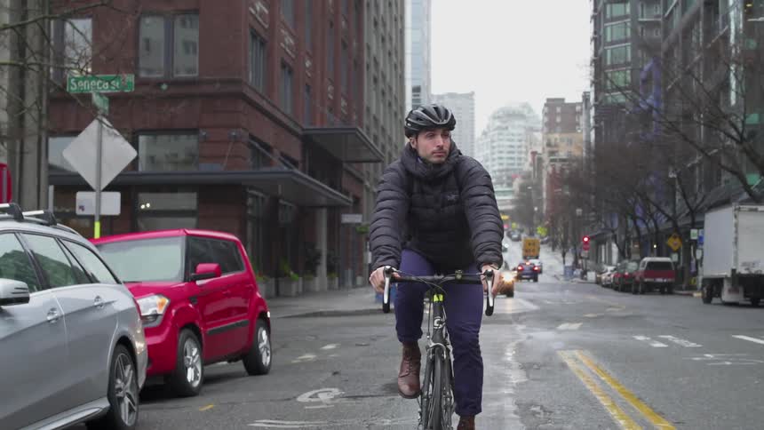 Man riding bicycle on city street on cloudy day
