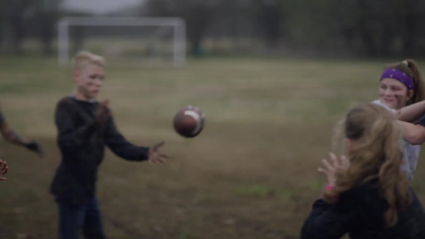 Children play football in a muddy grassy field