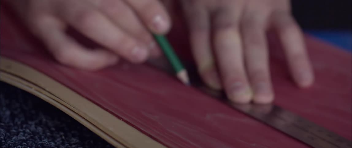 Person draws a line on fabric using a pencil and a ruler