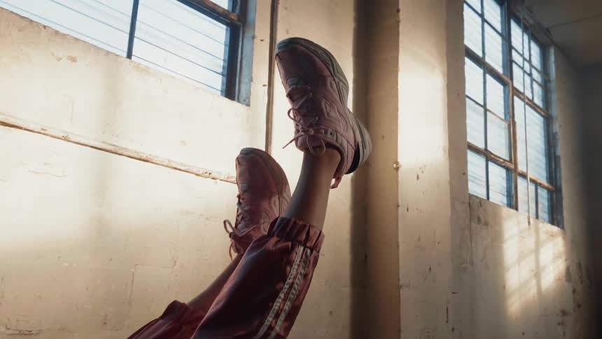 A woman wearing sneakers lies with her feet up in the air