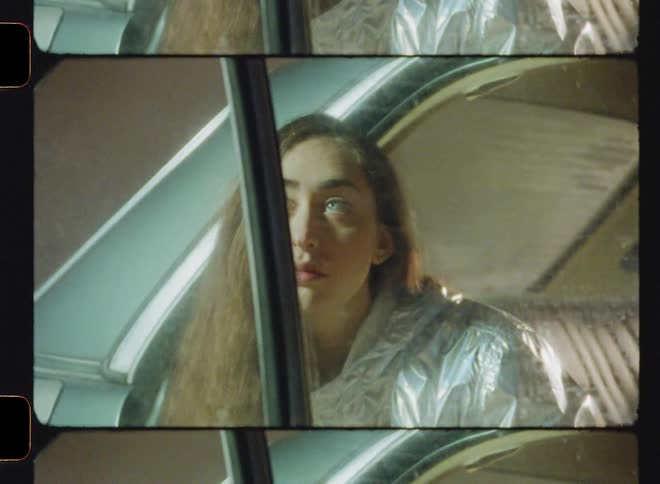 Woman sits in car with the door open and looks around