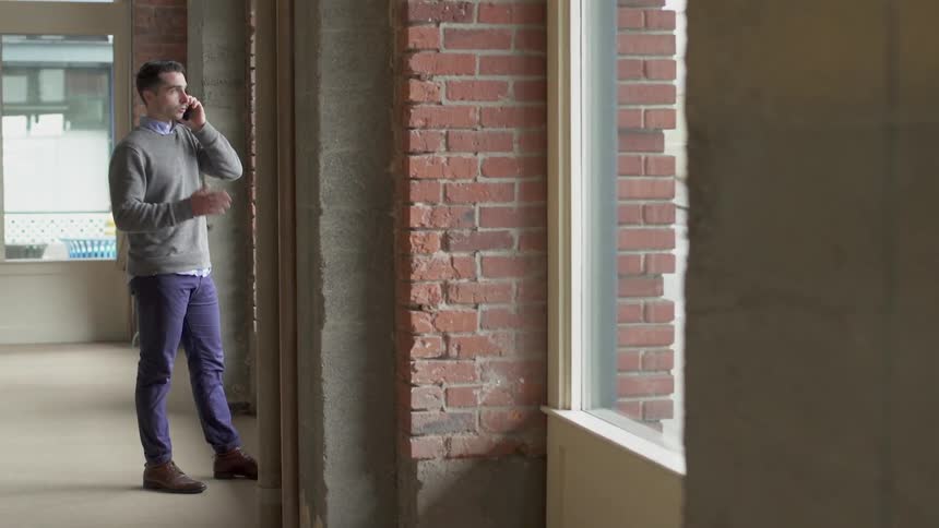 Man talks on cell in an empty apartment
