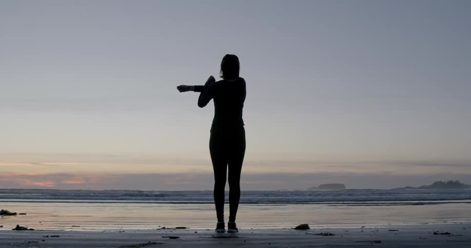 A person is stretching by the shore