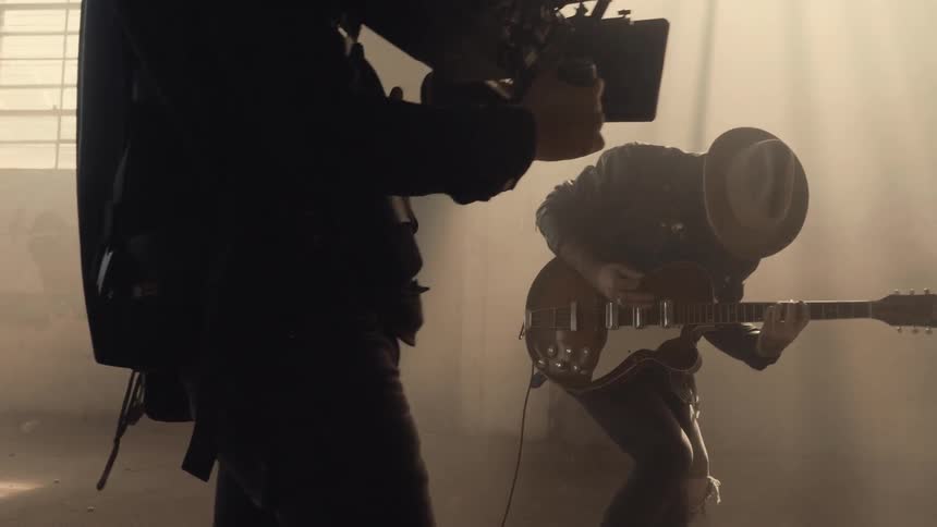 He performs with his guitar as he is filmed
