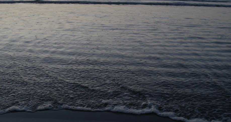 Ocean waves wash ashore at sunset