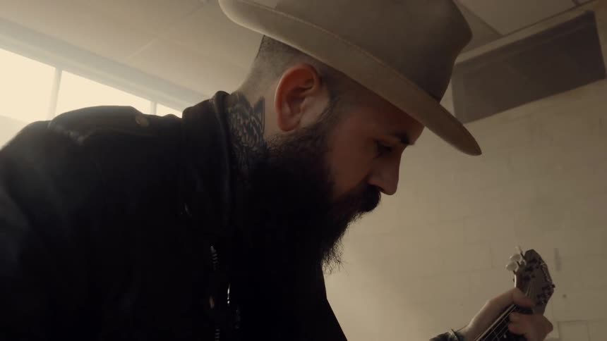 A man is playing the guitar wearing a hat