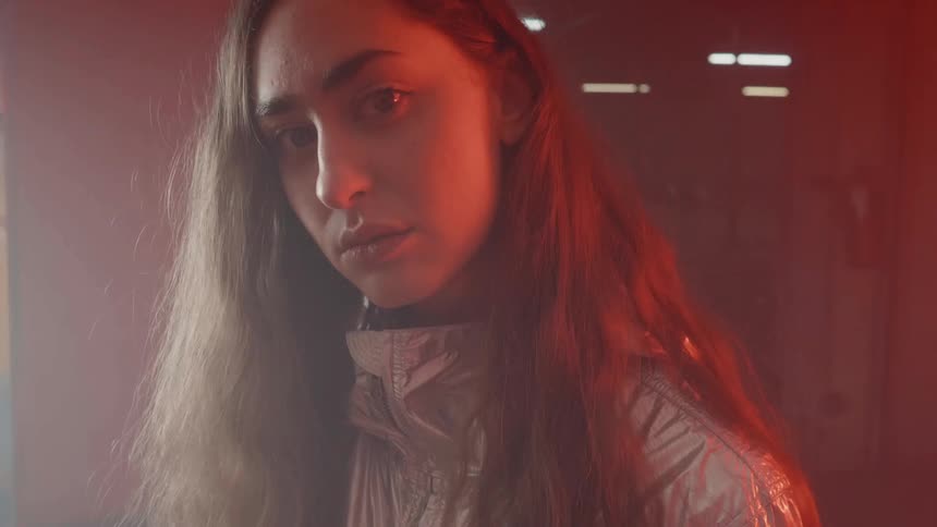A woman tilts her head as red and white lights flash