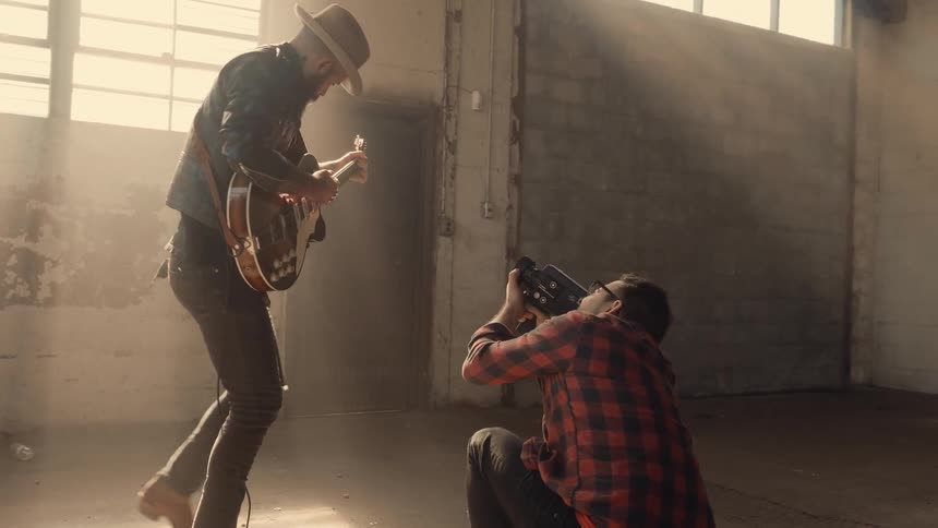 A man performs using a guitar as he is filmed
