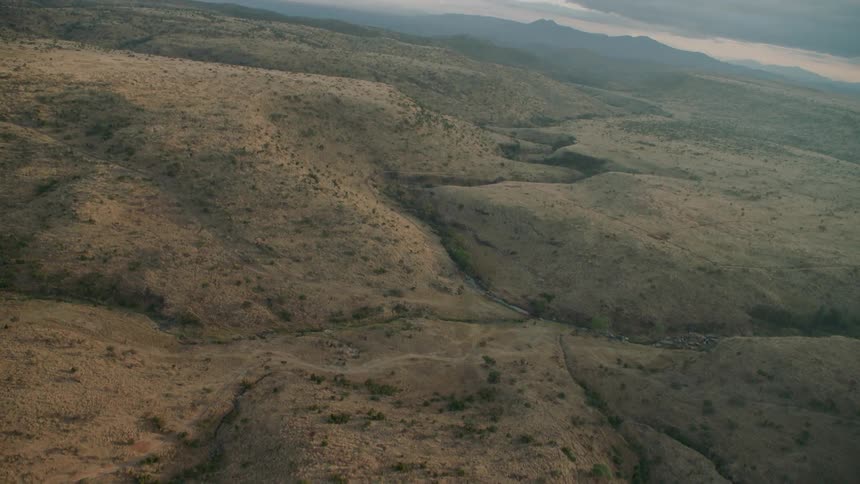 Dirt covers a hilly landscape at sunset