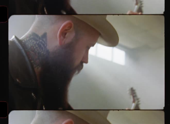 A man plays guitar in an empty room with sunlight coming through windows