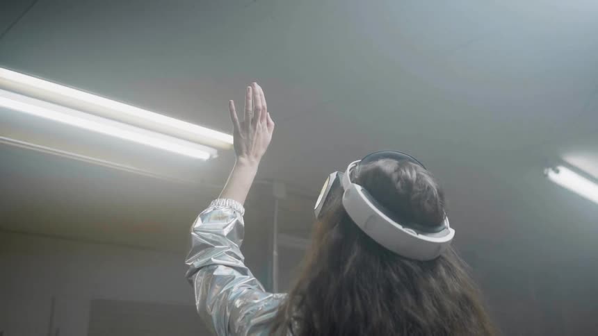 Woman is reaching up with her hand while wearing virtual reality headset