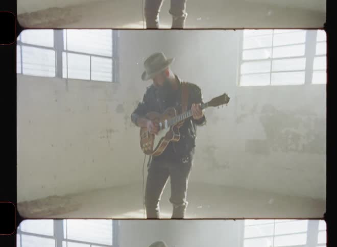A man plays a guitar in a sunlit room