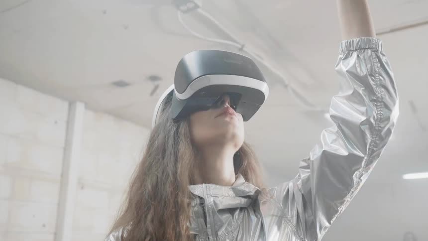 A woman wearing a virtual reality headset reaches up