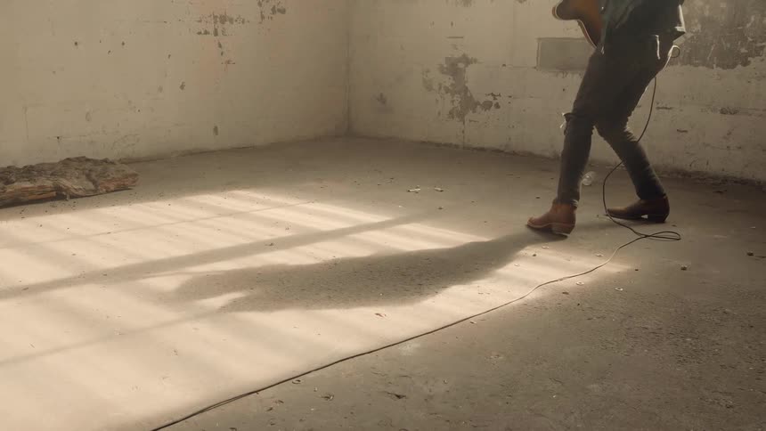A guitarist plays in an empty room