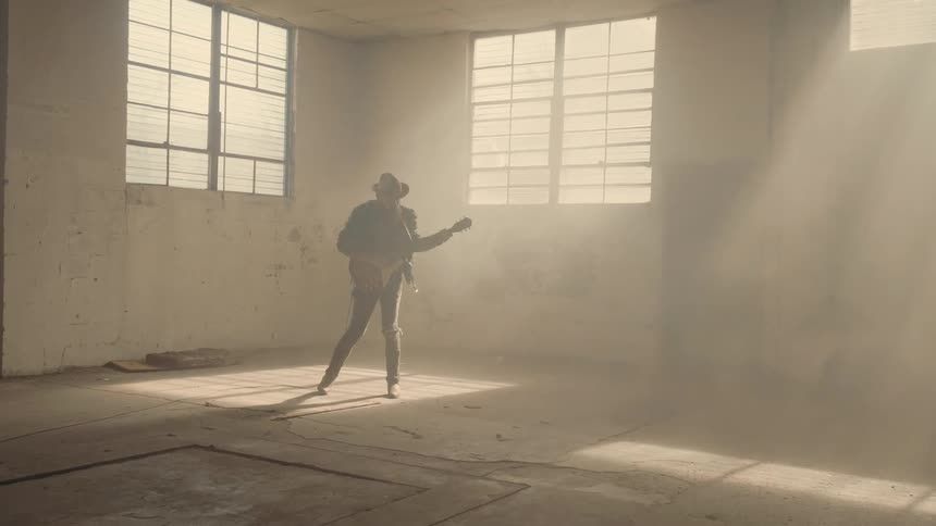 Man plays guitar in an empty room