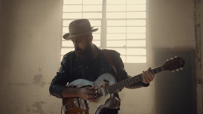 A man plays guitar in a run down building