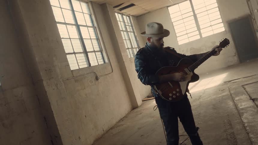 Man stands in an empty room playing a guitar