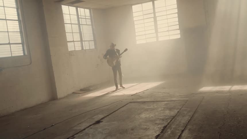 Man plays guitar in a dusty warehouse