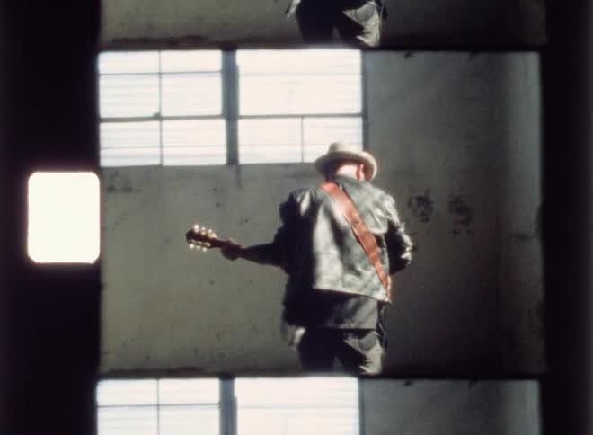 A man plays guitar inside a rundown building