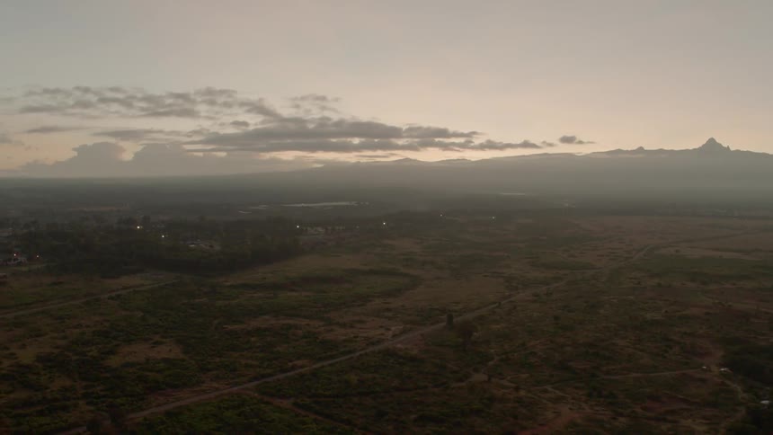 The sun is setting over the vast green fields