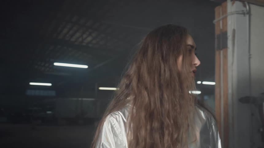 A woman stands in a warehouse with flashing lights