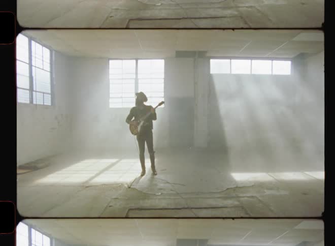A guitarist plays in a dusty warehouse