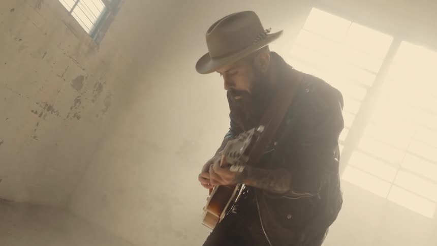 A man sways back and forth jumping and playing guitar
