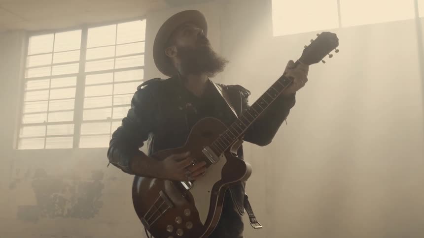 Guy plays the electric guitar in an abandoned building