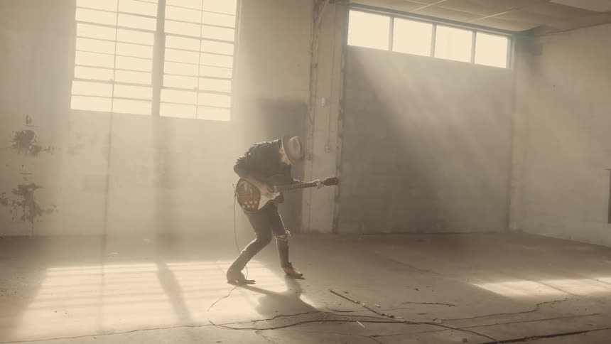 A man is playing guitar and jumping as he dances