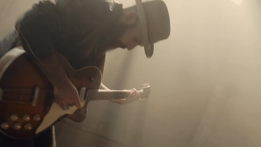 A man is dancing in the large room playing guitar