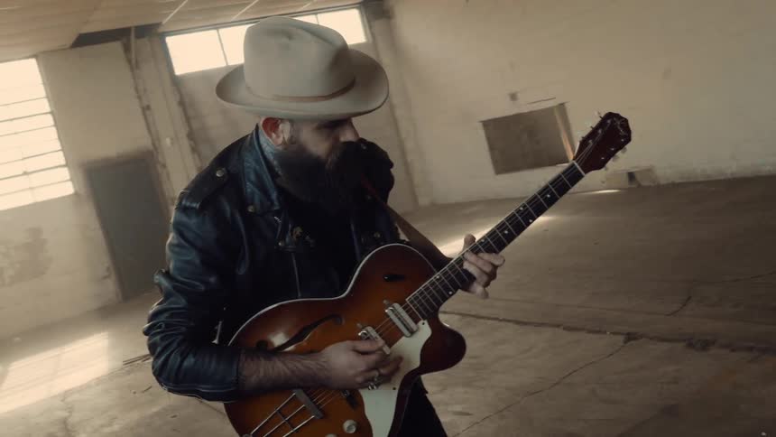 A man with a beard is playing a guitar