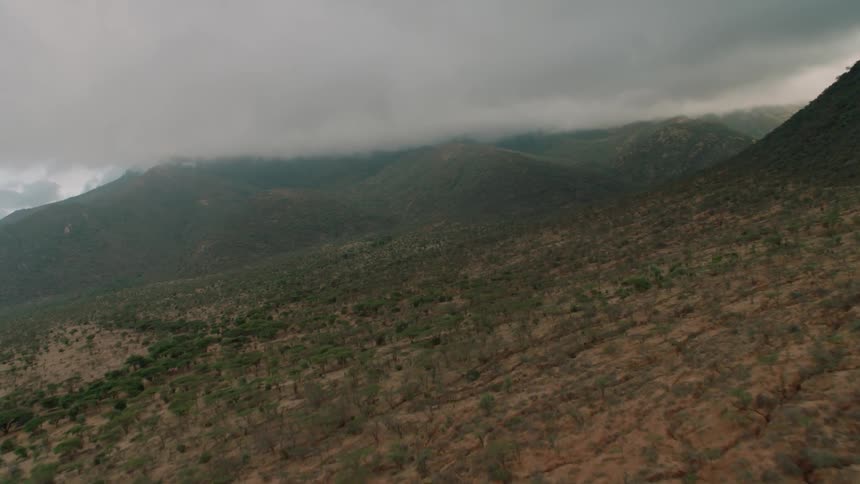 Brushy land and mountains with clouds hovering low