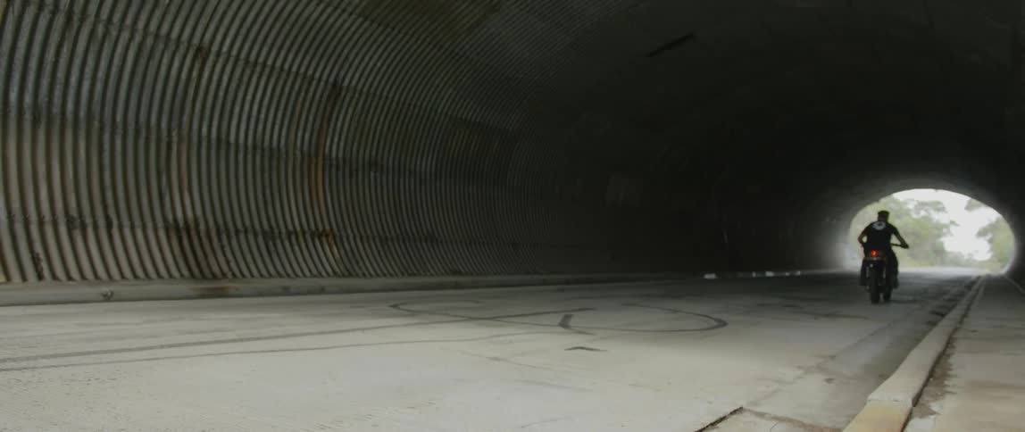 A man motorcycles through a tunnel