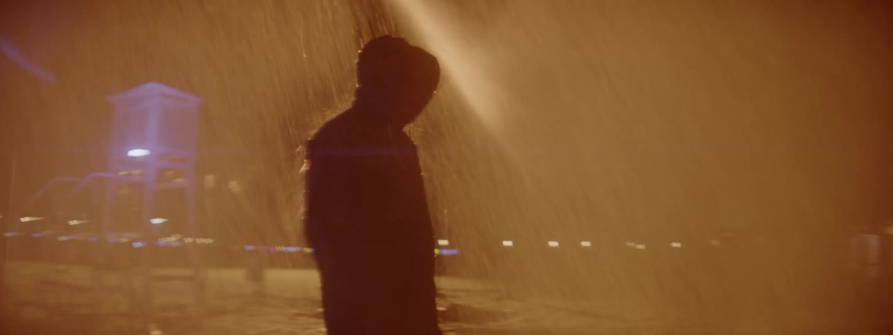 A man is checking equipment at night in the rain