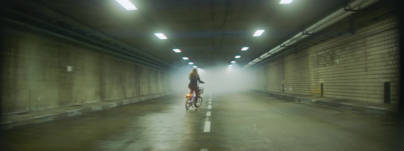 Woman riding a bike in a tunnel towards fog