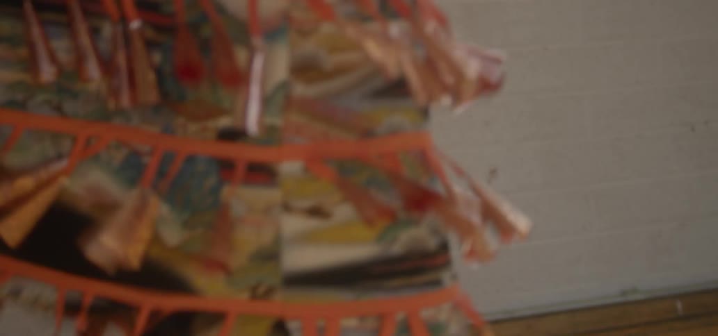 An american indian woman wearing a native costume is dancing indoors in daylight