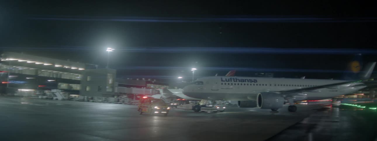 An airplane is being guided away from an airport terminal at night
