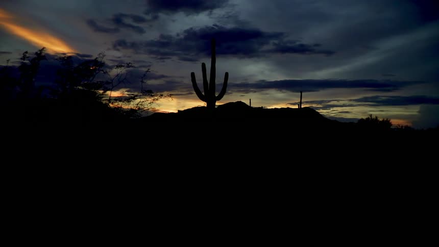 Clouds float above a desert at dusk