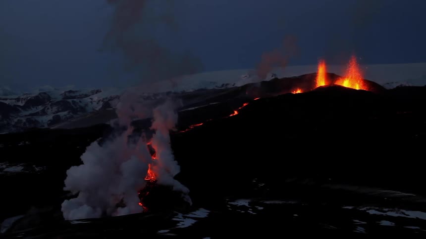 A volcano is erupting with lava pouring down the hill at dawn