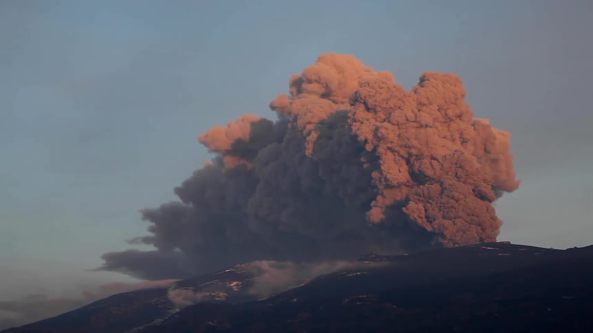 Smoke from a brush fire is billowing up into the sky in daylight