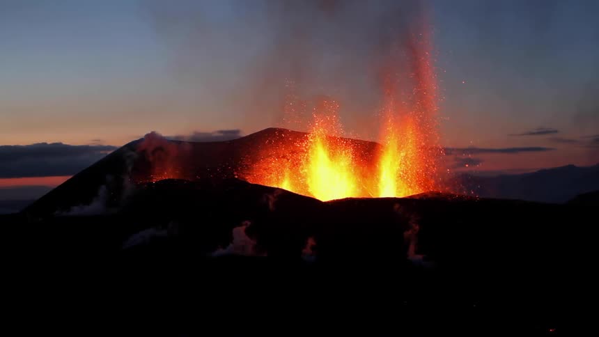 Lava erupts from a volcano at dusk