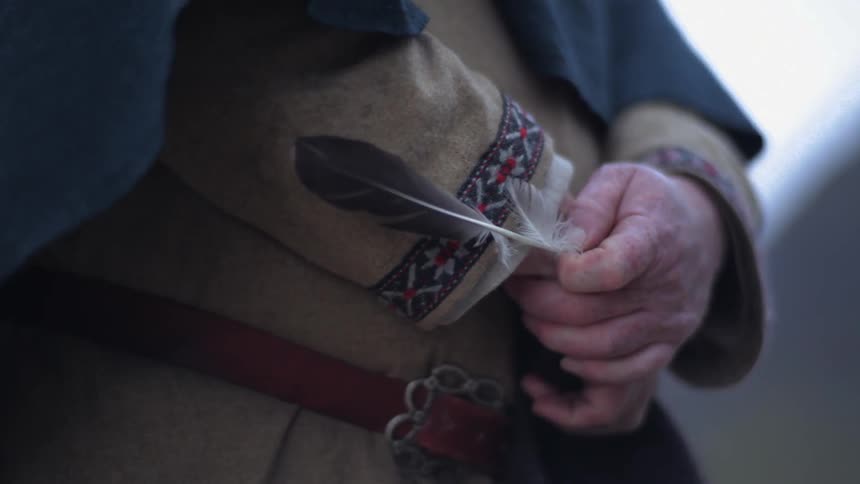 A man holds a birds feather in his hand