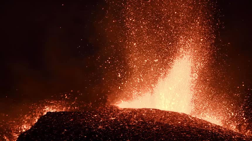 Lava is bursting from a volcano fissure at night