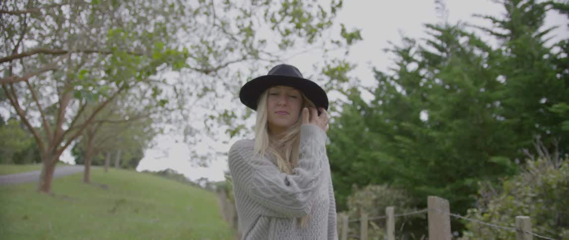 Woman walking on a field alongside a fence