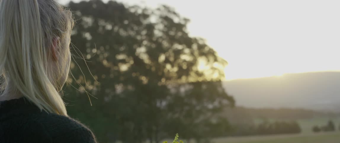 A woman looks towards a sunset
